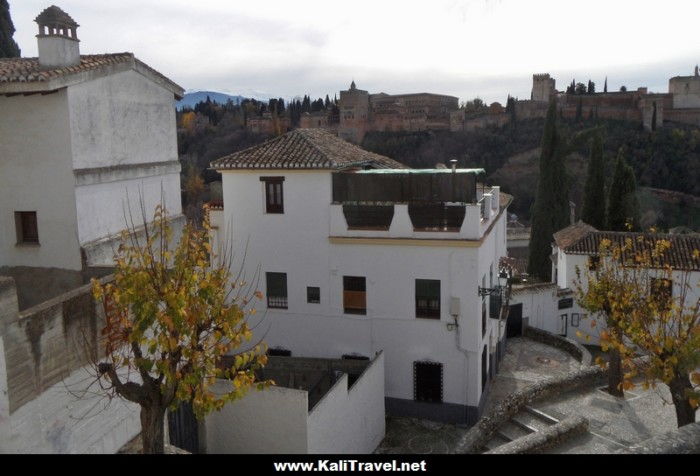 Casas blancas en barrio antiguo con vistas del Alhambra.