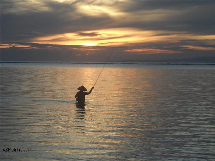 Fisherman in the sea at sunrise in Sanur beach.