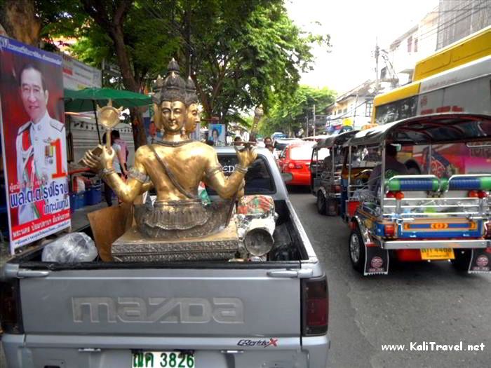 Golden Buddha statues being carried on a truck in the streets of Bangkok.