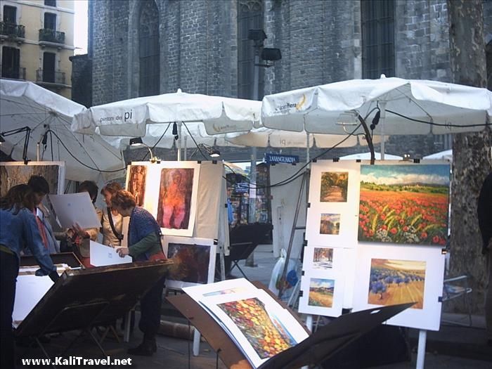Paintings on artists stalls in front of a medieval building.