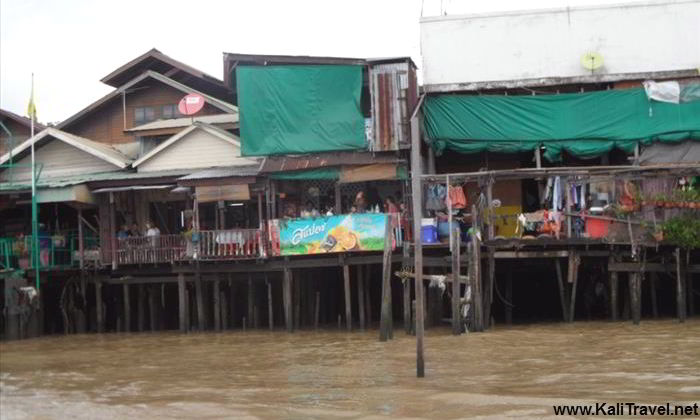 Old traditional wooden Thai houses on stilts beside Chao Phraya River in Bangkok.