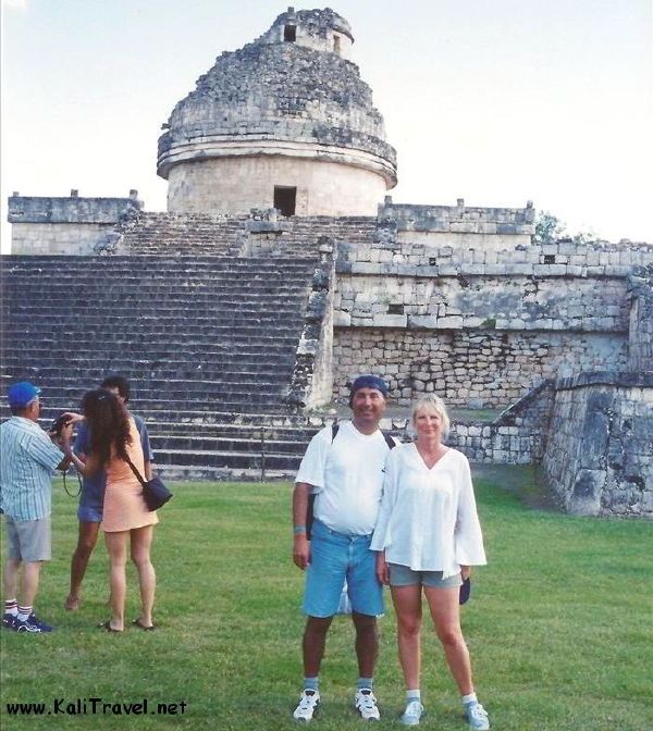 Couple standing in front of Chichen Itza ruins.
