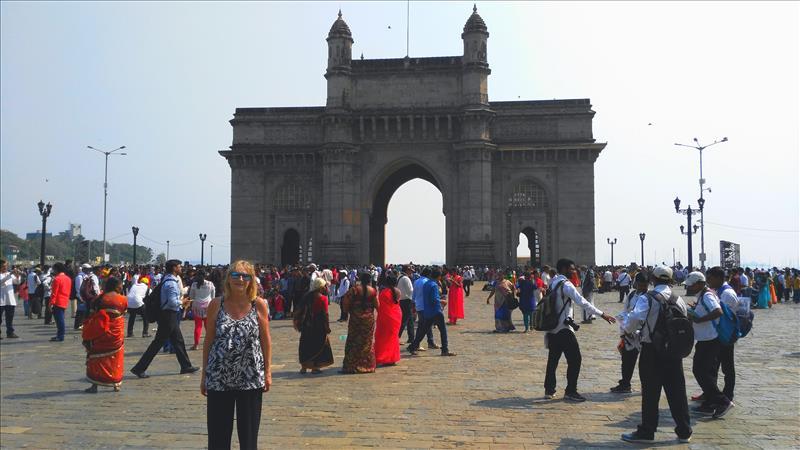 Tourists standing in front of the giant Gateway of India in Mumbai.