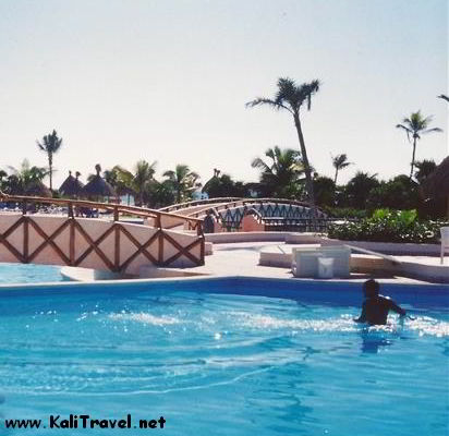 Swimming pool in Riviera Maya hotel gardens with palm trees.