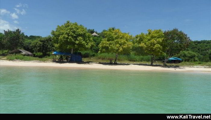 Little beachbar on the sands of a pink beach lined by trees.