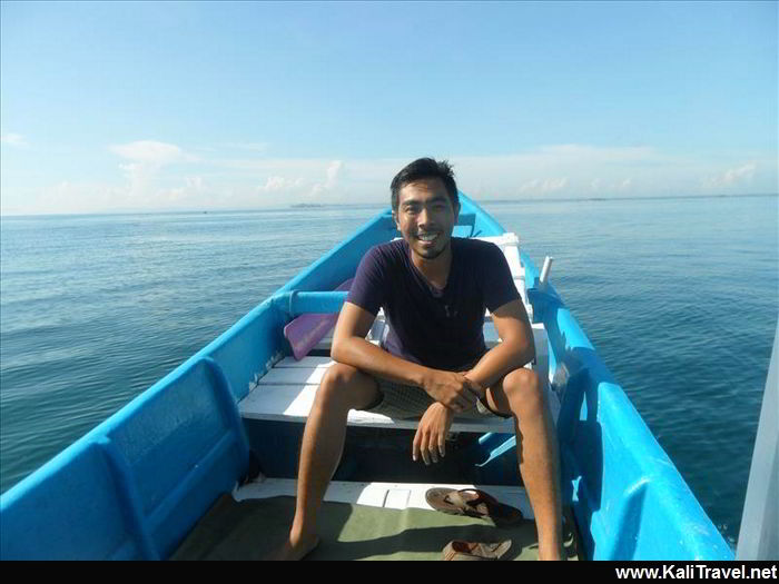 Male guide Eka Senggigi sitting on a small boat in the sea.