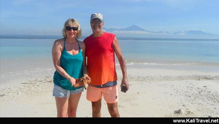 Couple standing on a pink beach sandbank with a giant starfish.