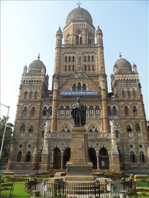 The 3 towers of Mumbai's Municipal Corporation Building with a scholarly statue outside.