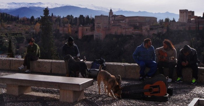 Gente sentado con un perro en la plaza con vistas al Alhambra y la Sierra Nevada.