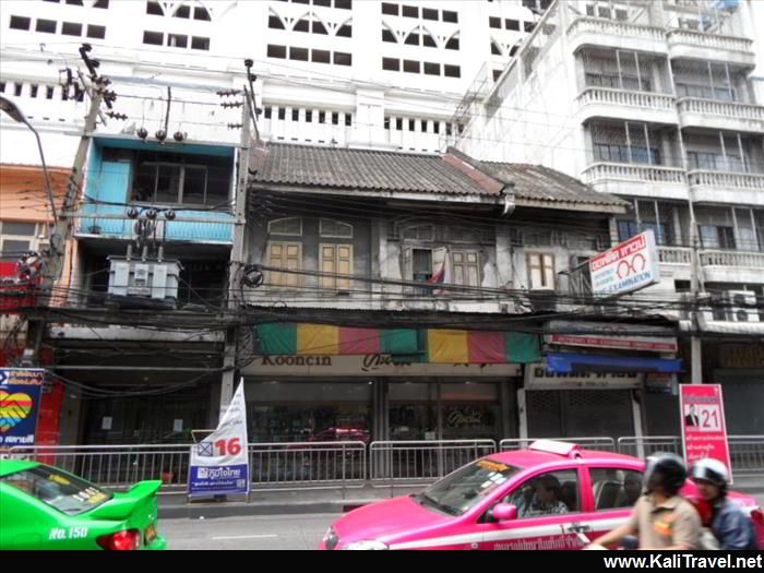 Bright coloured taxis passing old traditional buildings on Silom Road in Bangkok city centre.