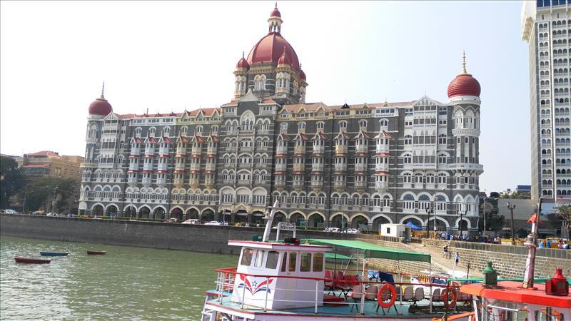 Tourist boat by Mumbai seafront with the Taj Hotel in the distance.