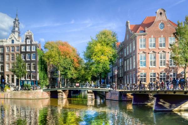 Amsterdam canal, stone bridge with bicycles, medieval buildings.