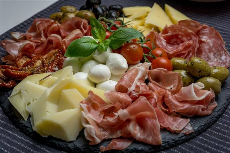Plate of Parma ham and Italian cheeses in Bologna, one of the best places for food in Emilia Romagna.