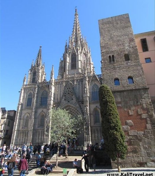 People on the steps of the Gothic Cathedral ornate entrance beside the towers.