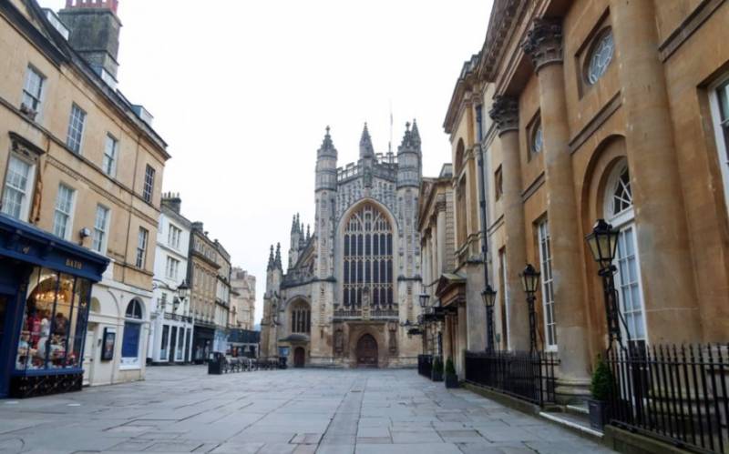 The tower of Somerset's Bath Abbey Cathedal at the end of a cobbled street.
