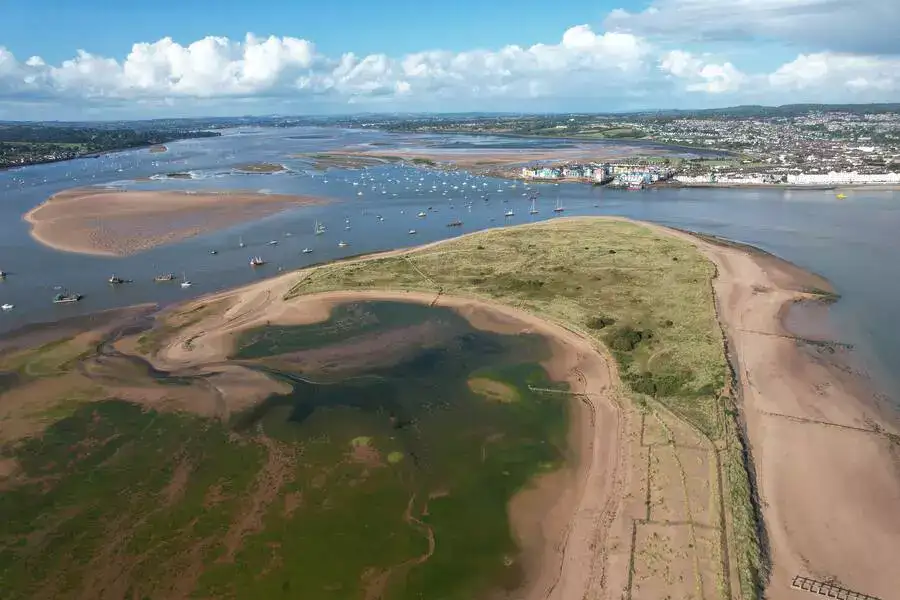 Aerial view over sandy river estuary with lots of little boats.