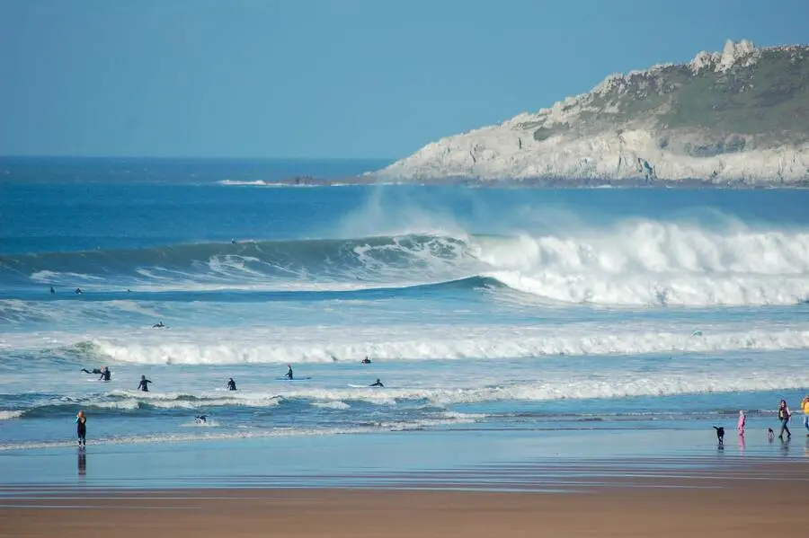 Sandy beach with surfers in the sea.