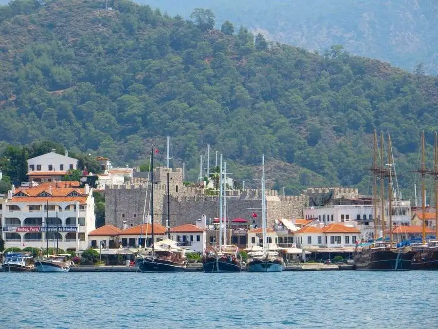 View across the sea to boats and a castle on Turkey's turquoise coast.