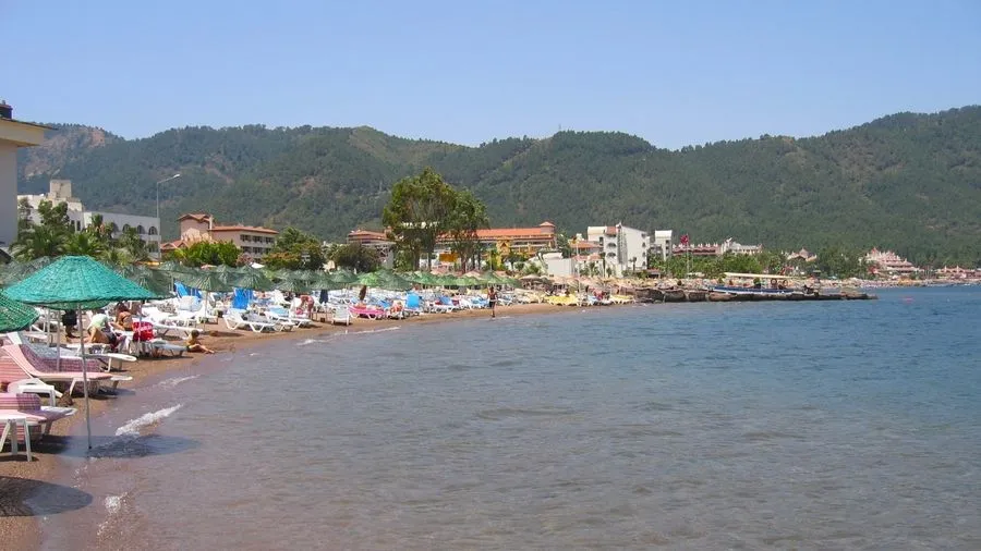 Nice sandy beach with sun loungers by the turquoise sea and tree-clad hills.