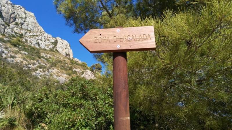 Wood sign points way to rock climbing zone at Sierra de Oltá in Calpe.