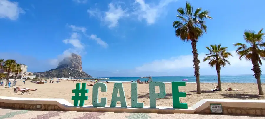 Huge green 'Calpe' sign in front of sandy Arenal-bol beach.