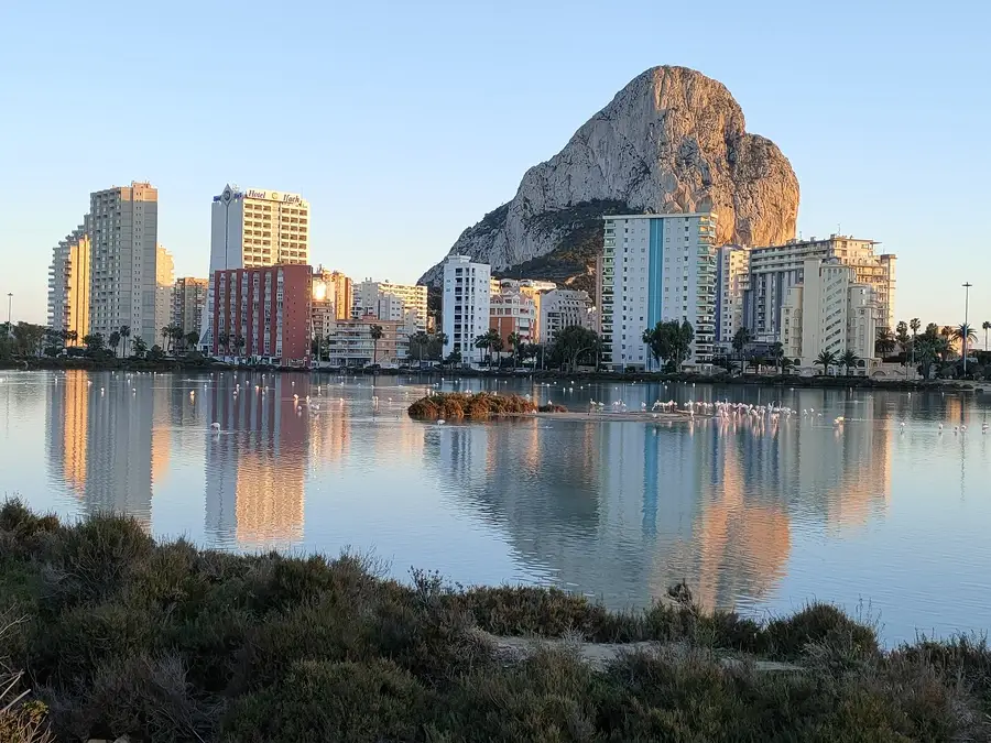 Calpe salt lake with flamingos, and huge 'rock' towering over highrise hotels.