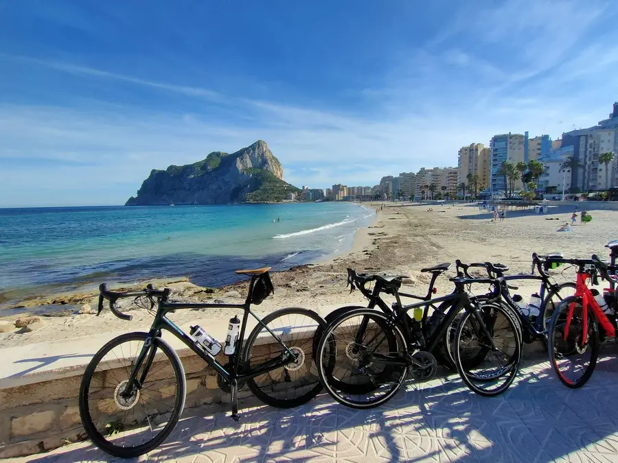 Cycles beside sandy Levante beach with massive 'Calpe rock' rising from the sea.
