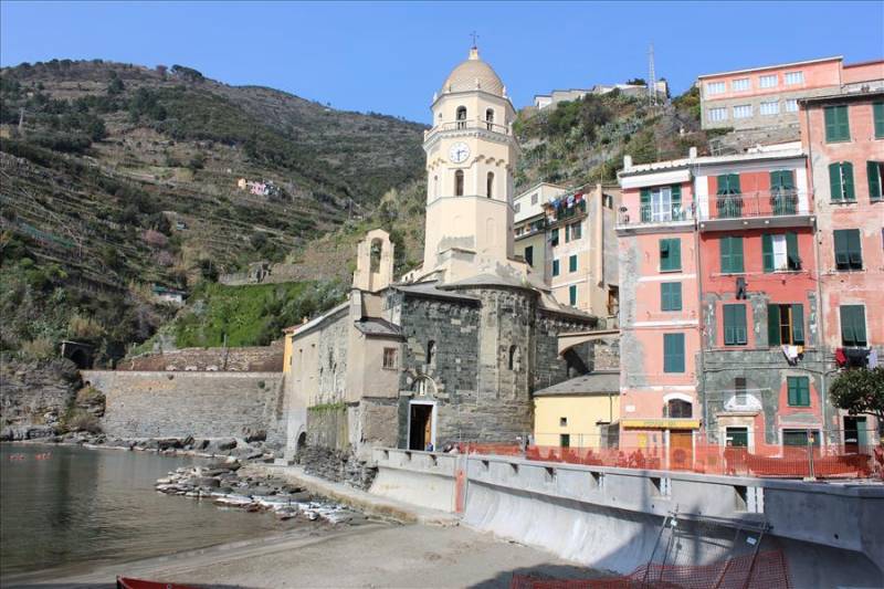 Seafront with ancient church clocktower in Cinque Terre on Italy's Ligurian coast.