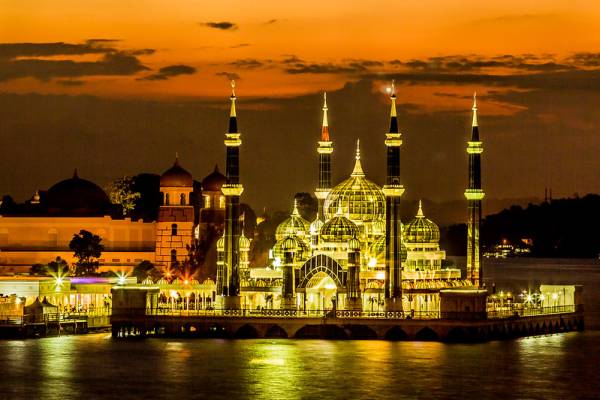 The unique Crystal Mosque relecting on the water at sunset in Malaysia.
