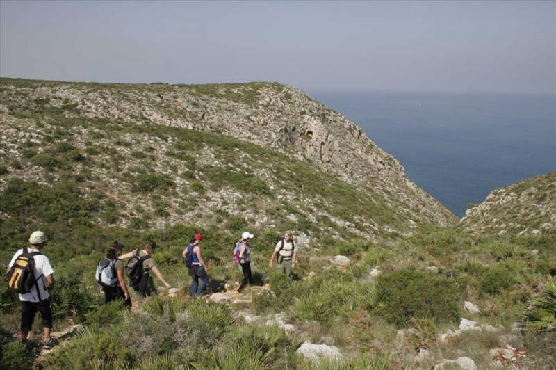People hiking Dénia's Mount Montgó trail by the sea.