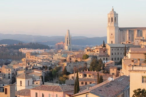 Rooftops and church spires of medieval Girona at sunset.