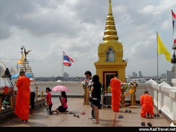 Orange-robed monks praying on the roof terrace of the Golden Mount Temple in Bangkok.