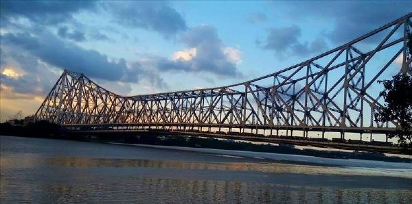 Red steel Howrah Bridge suspended over River Hooghly in Kolkata.