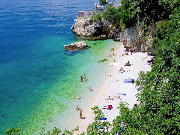 Blue green sea, white beach under cliffs in Croatia.