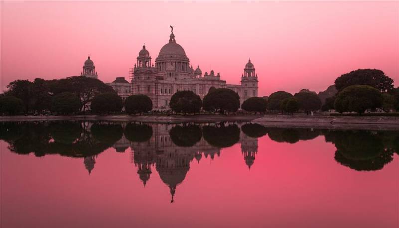 Victoria Memorial reflecting a pink sunset in the river, Kolkata.