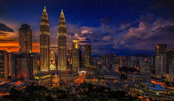 Unique Malaysia cityscape of Kuala Lumpur lit up at dusk.
