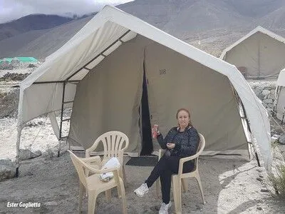 Mujer sentada en una silla afuera de una tienda de campaña.