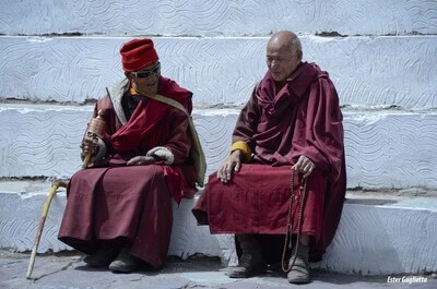 2 monjes Budistas vestidos con tunicas color granate, sentados en un escalon.