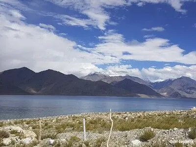 Lago con montañas al fondo y cielo nuboso.