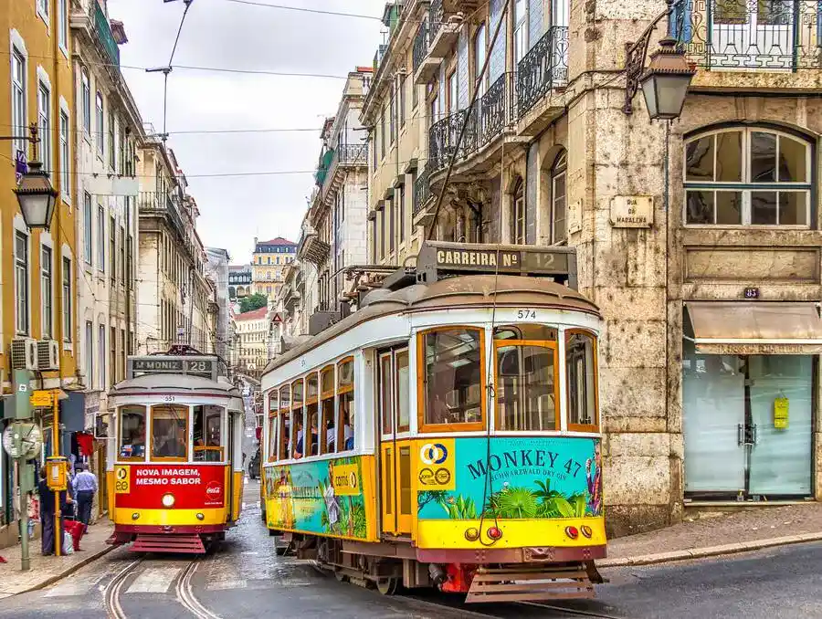 2 colourful trams in Lisbon historic quarter.