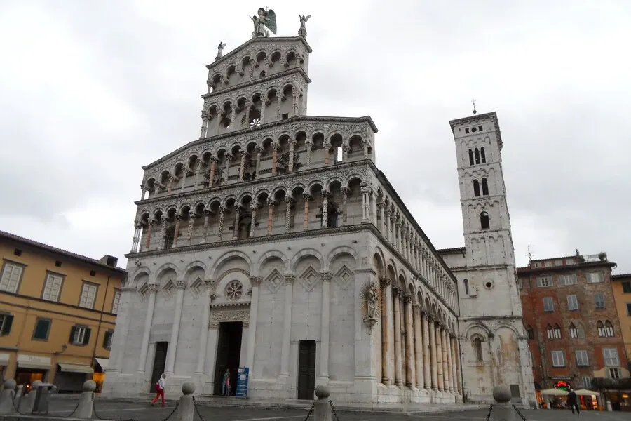 White marble façade of San Michele in Foro church in a medieval street.