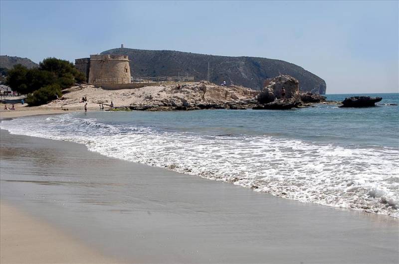 Sands, sea and ancient watchtower at L'Ampolla beach in Moraira, Costa Blanca.