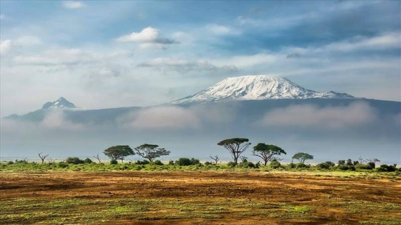 Snowy peak of Mount Kenya above clouds over the plains.