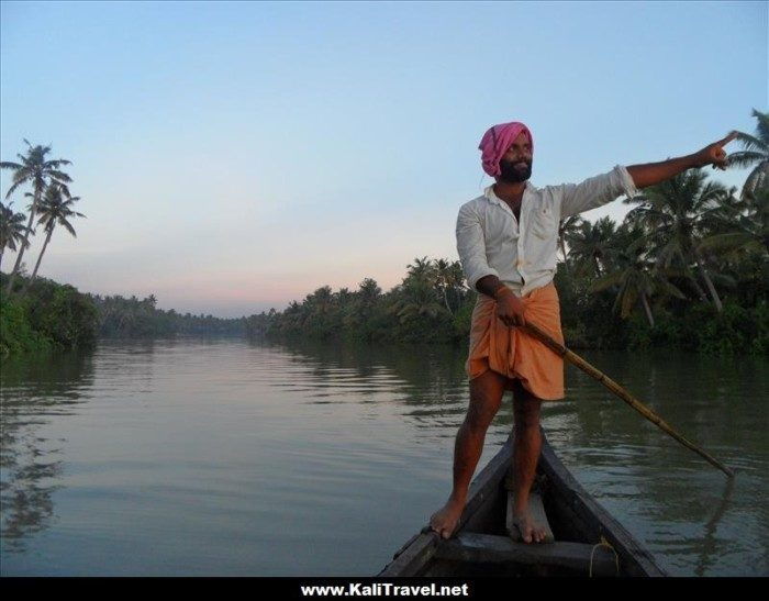 Indian boatman standing on a canoe at sunrise on the lake in Munroe island.