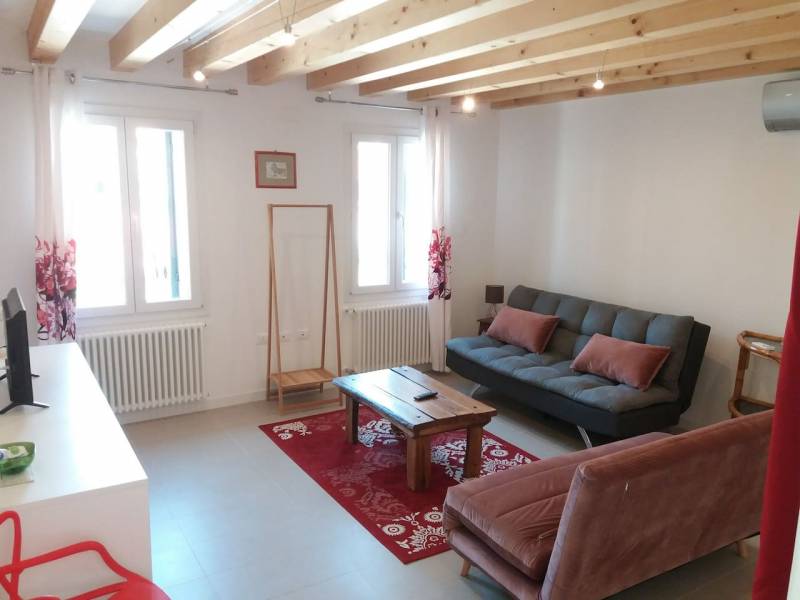 Giardino holiday apartment lounge with wood beams, black, white and red decor, Murano.