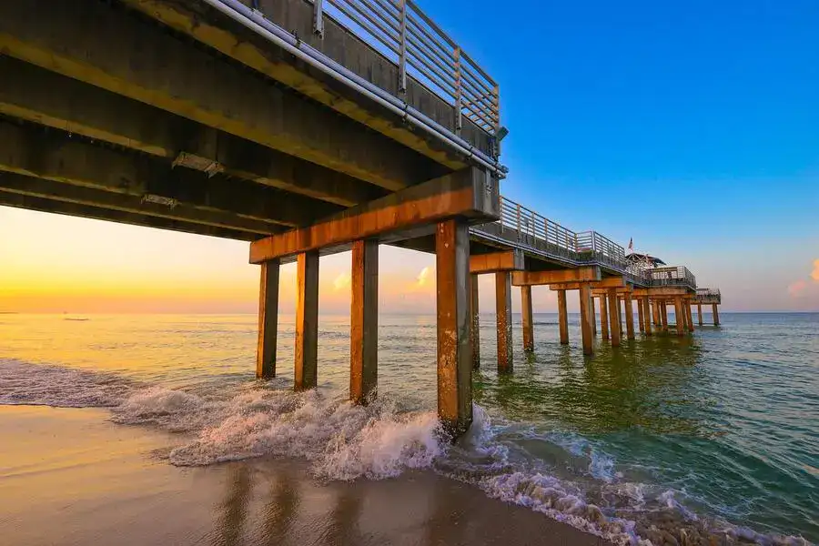 Wooden pier stretching into the sea on Alabama Gulf coast at sunset.