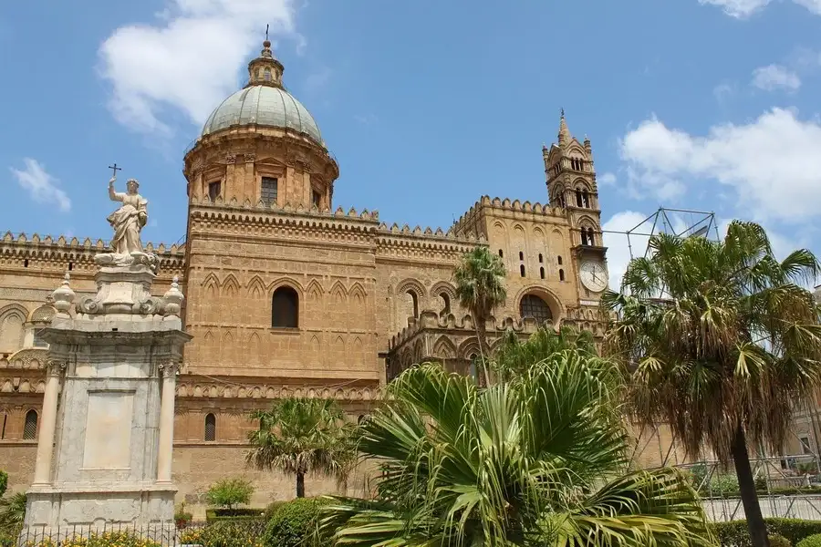 Palermo cathedral with palm trees against the blue sky in December.
