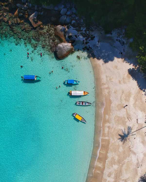 Little colourful boats on turquoise sea by white sands in Perhentian Islands, Malaysia.