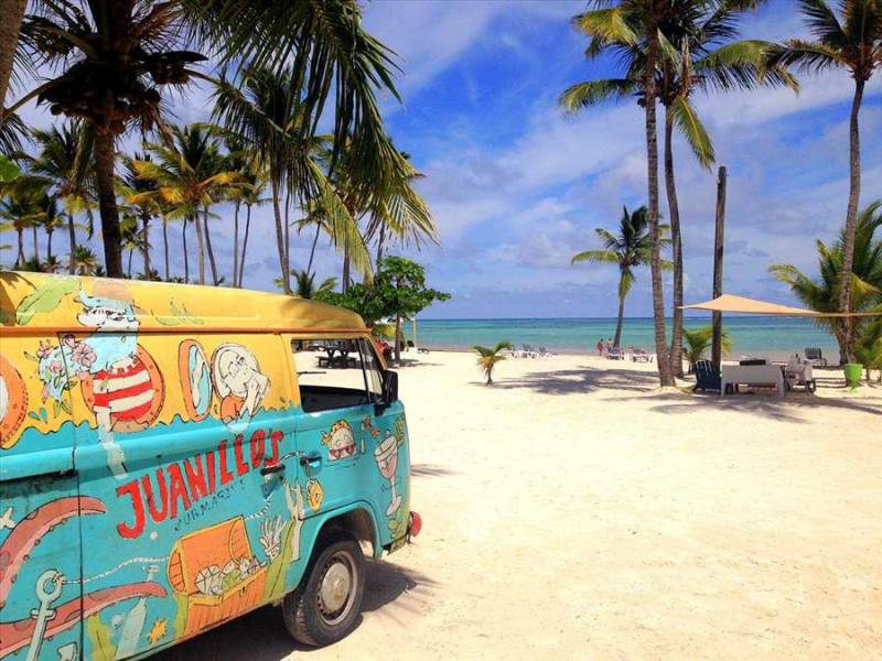 Multi-colour campervan on Playa Juanillo beach, Punta Cana.