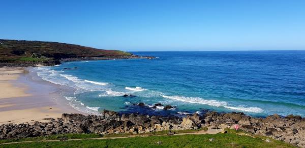 Waves surfing into Porthmeor sandy beach between cliffs in Cornwall.